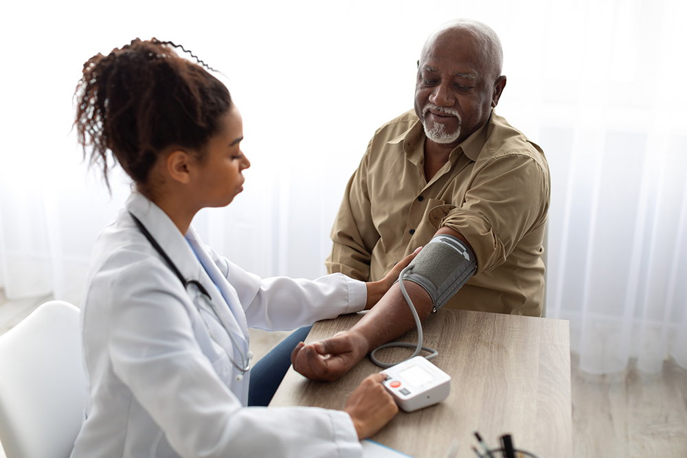 Eine Ärztin misst den Blutdruck eines älteren Patienten. 