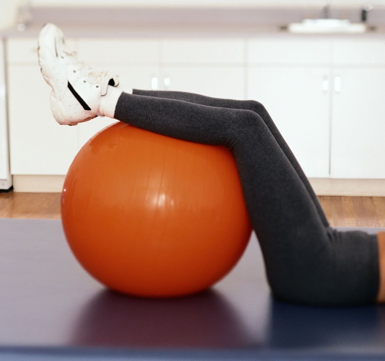 Beine einer Person liegen auf einem Gymnastikball. Therapiemaßnahme bei chronischen Schmerzen.