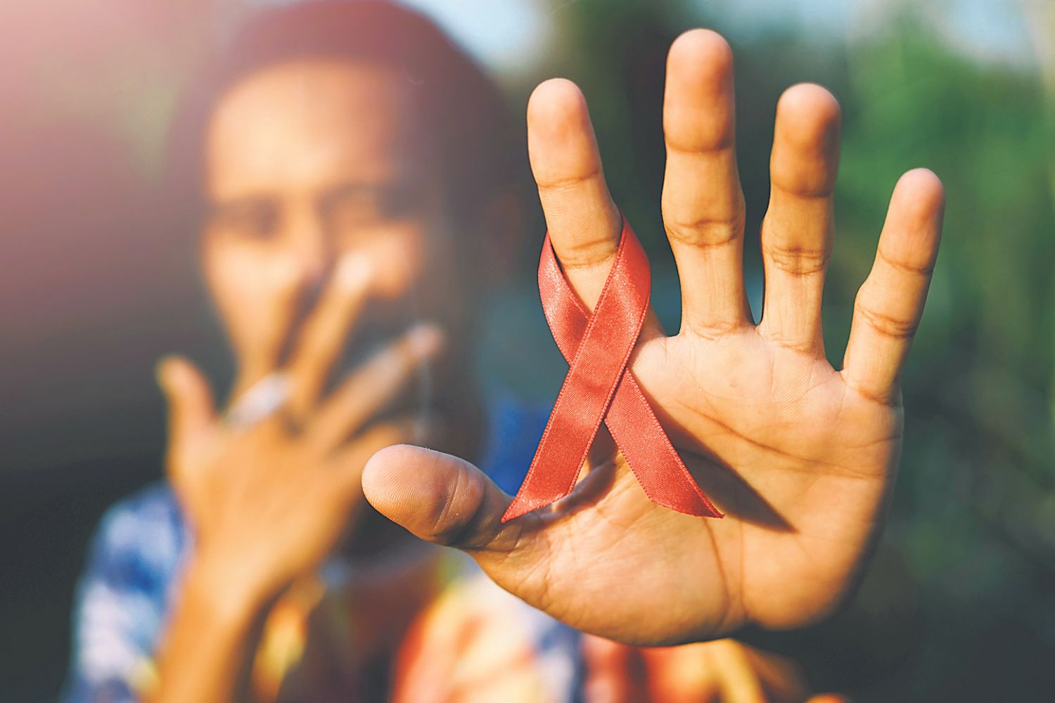 Eine Person trägt die Aids-Schleife am Finger